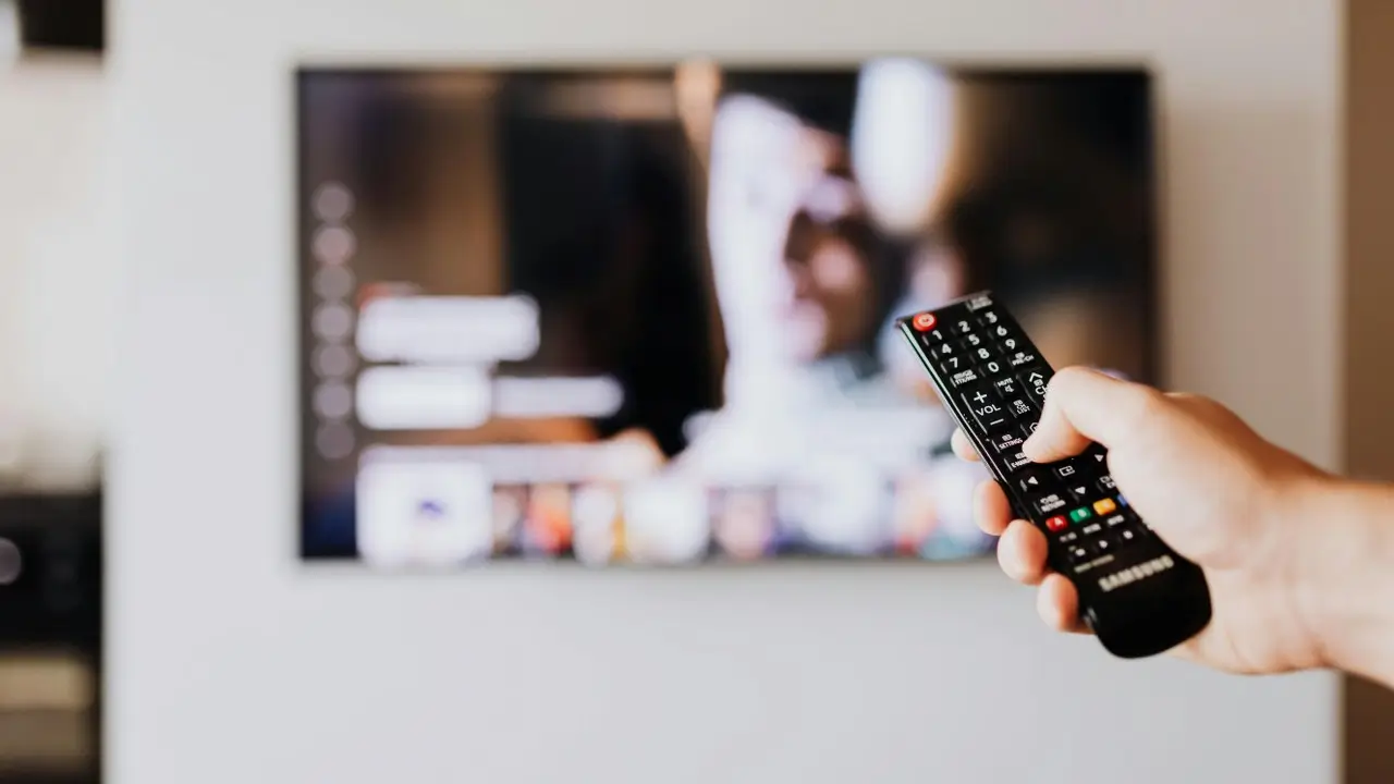 Ruka koja drži daljinski i mijenja tv kanale