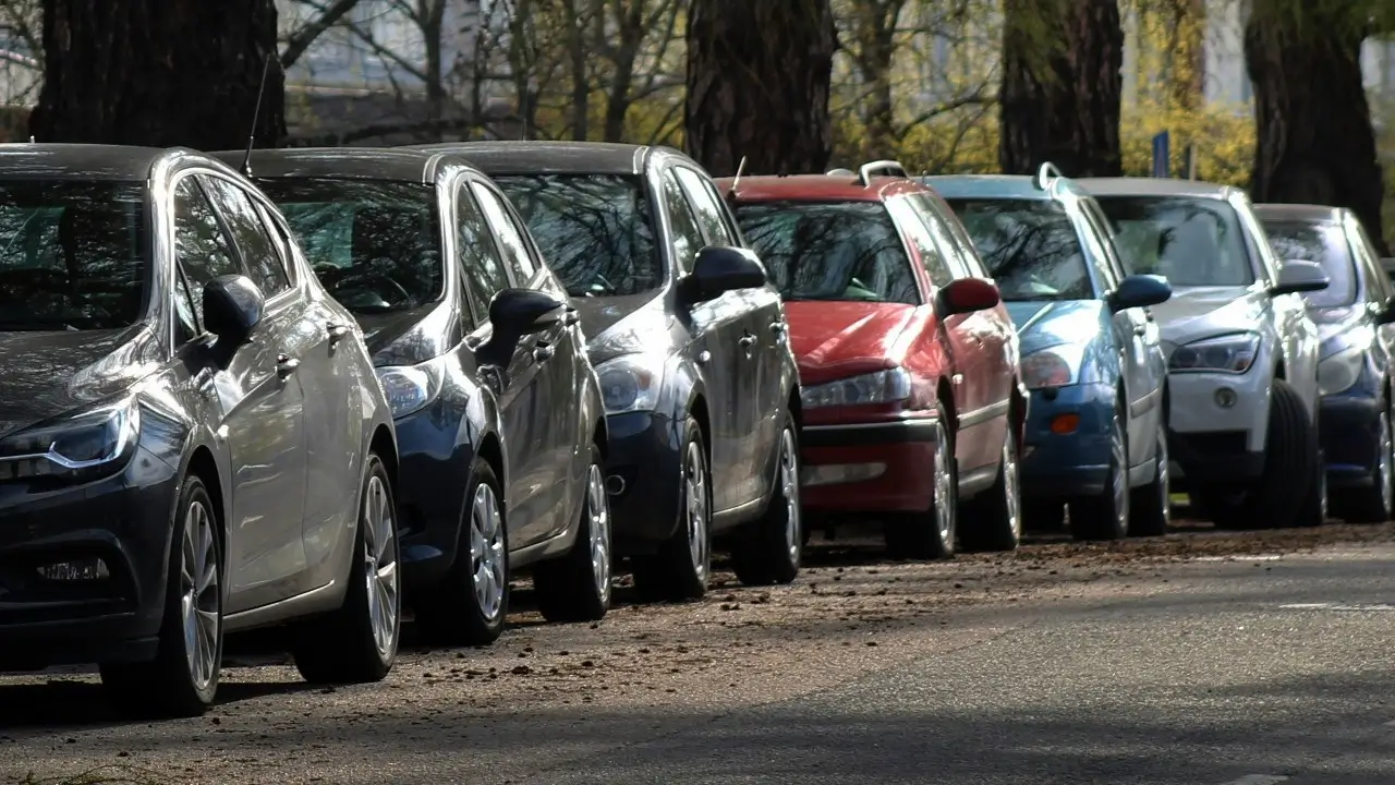 Niz parkiranih putničkih automobila na javnom parkingu, ilustracija velikog broja službenih vozila u državi.