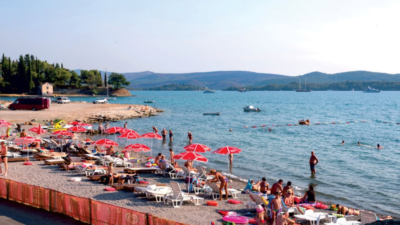 Ljetovanje u Tivtu: Šta vas čeka i koliko košta Tivat je posljednjih godina postao jedna od najatraktivnijih destinacija na crnogorskom primorju. Ako izuzmemo luksuzne komplekse poput Porto Montenegra i Luštice Bay, evo kratkog pregleda cijena kako biste lakše isplanirali budžet za odmor: Hrana i obroci: • Doručak: oko 4 do 6 eura po osobi (kompletan doručak za četvoročlanu porodicu iznosi od 15 do 25 eura). • Pica i dnevni obroci: najčešće od 7 do 12 eura, dok su restorani u samom centru i na šetalištu nešto skuplji. Kafa i piće: • Kafa: od 1,10 do 1,80 eura u većini lokalnih kafića, dok je na plažama cijena uglavnom oko 2 do 3 eura. • Osvježavajuća pića i pivo: najčešće od 3 do 5 eura. Plažni mobilijar: • Komplet (dvije ležaljke i suncobran): na uređenim plažama van luksuznih zona kreće se od 15 do 25 eura, dok zakup baldahina i mjesta u fensi plažnim barovima ide znatno naviše. Smještaj (prosječne cijene za apartman za 4 osobe po danu): • Gradiošnica i Dumidran (malo dalje od mora): oko 120 eura dnevno. • Centar Tivta: oko 160 eura dnevno. • Seljanovo i Donja Lastva: oko 180 eura dnevno. • Luštica: od 100 do 140 eura dnevno, u zavisnosti od blizine obale.